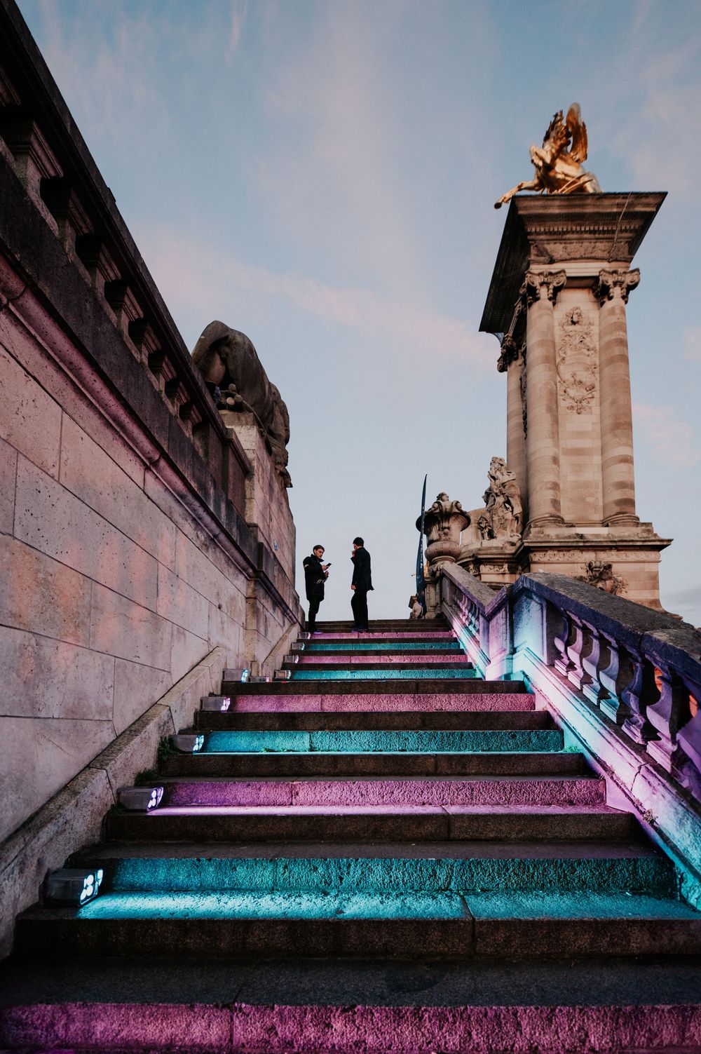 Colorfully lit stone staircase with silhouetted figures at historic monument.