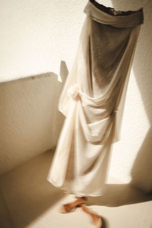 Elegant cream draped skirt with floral detail, photographed in soft natural light against a white textured wall.