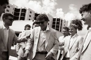 Group of men in suits socializing outdoors in black and white photo at a formal event.
