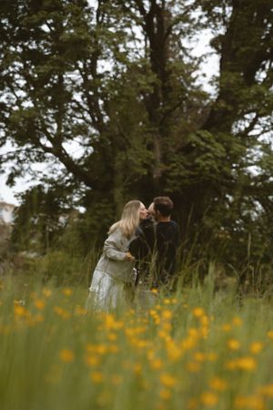 Family candidly kissing their baby in a field of yellow flowers.