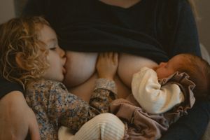 toddler girl and newborn baby tandem breastfeeding during at-home newborn session