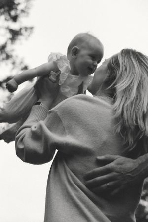 black and white interesting angle shot of a mother holding her baby in the air