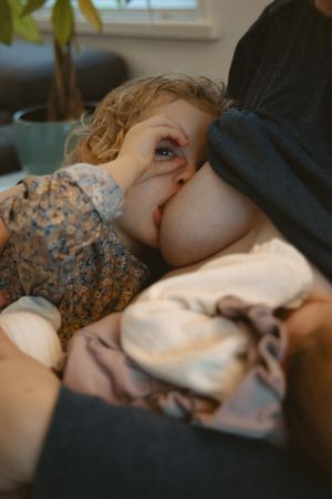 candid moment during a newborn photoshoot at home with the toddler also breastfeeding and making fun of the camera