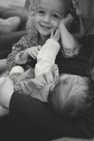 black and white photo from a newborn session where the mom was able to tandem feed her two week old baby and three year old toddler
