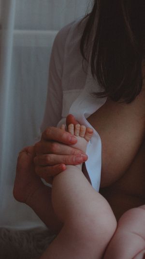 Close up of baby's foot being held softly while nursing
