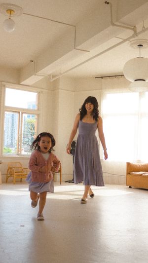 A playful moment of a toddler girl running away from their mom during a motherhood photoshoot