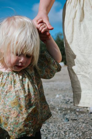 A candid hand-holding moment between a toddler and their pregnant mom during a documentary-style family photoshoot.