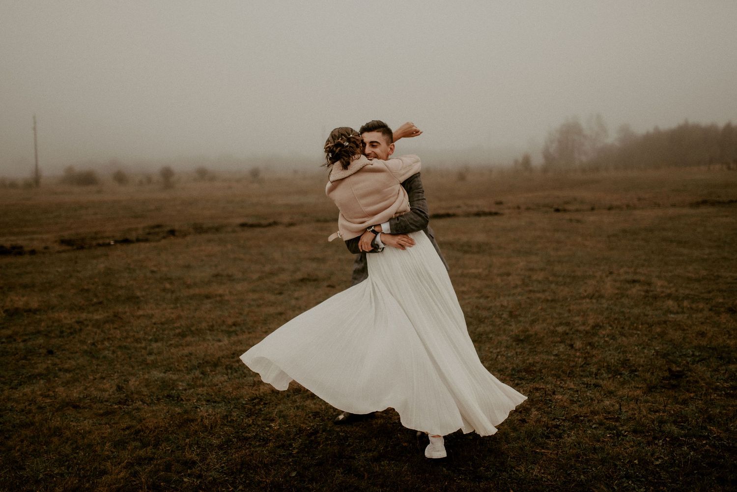 Flowing white dress twirling in a misty field during a moody outdoor photoshoot.