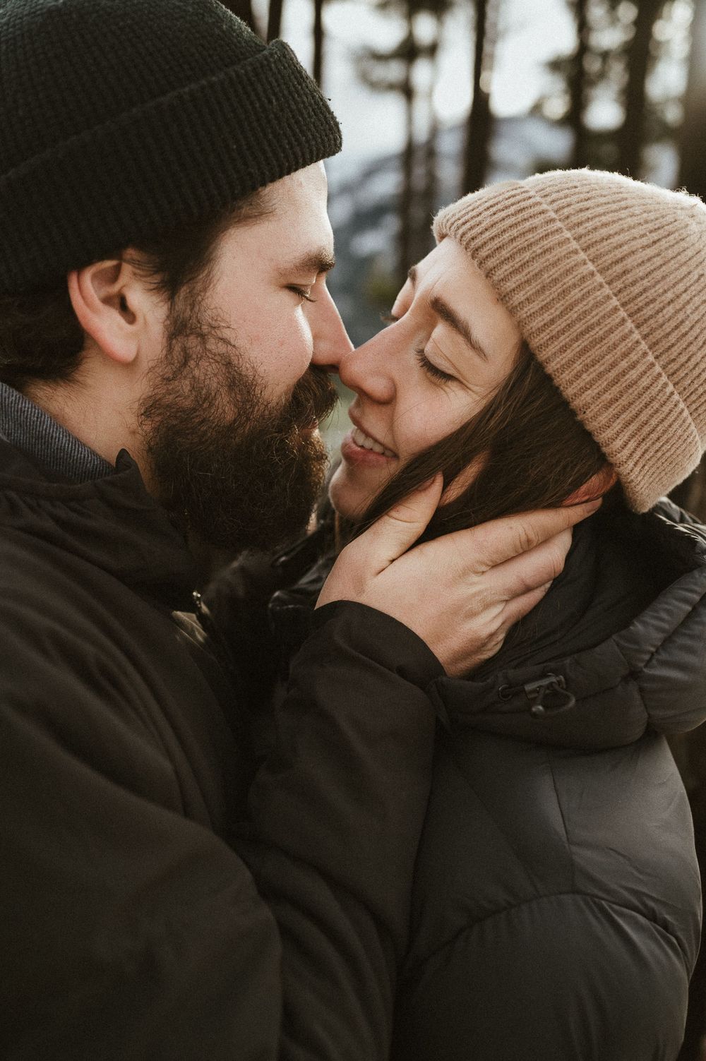 Cozy winter portrait of couple in knit beanies sharing intimate moment outdoors.