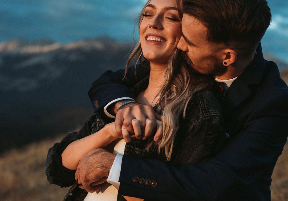 A joyful embrace captured against mountain peaks at dusk.