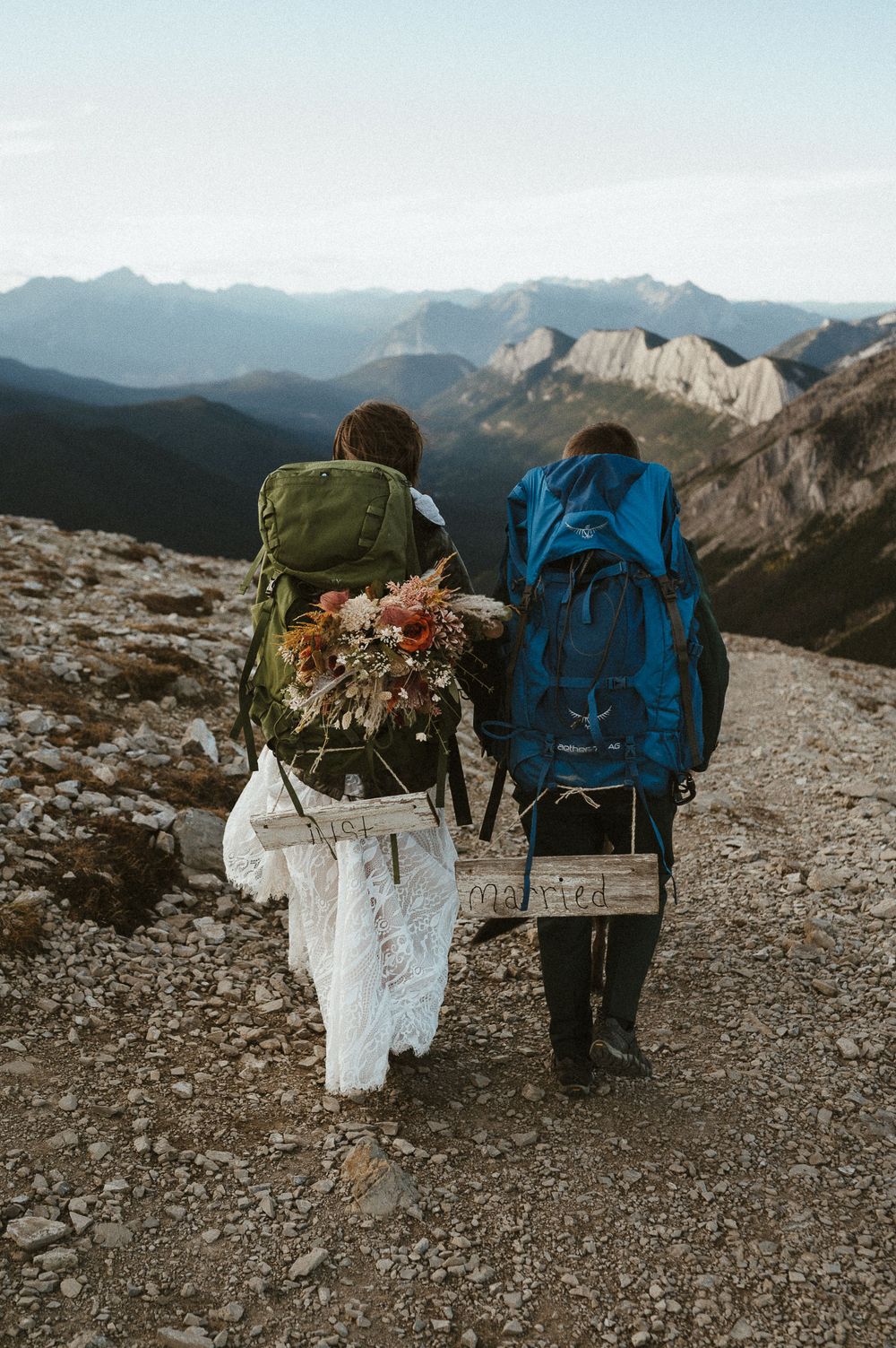 Two hikers with backpacks walking along a mountain trail overlooking a dramatic valley.
