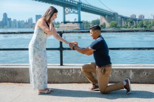 Proposal moment by waterfront with Manhattan Bridge in background.