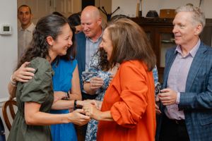 A lively indoor gathering shows people laughing and conversing at what appears to be a social event.