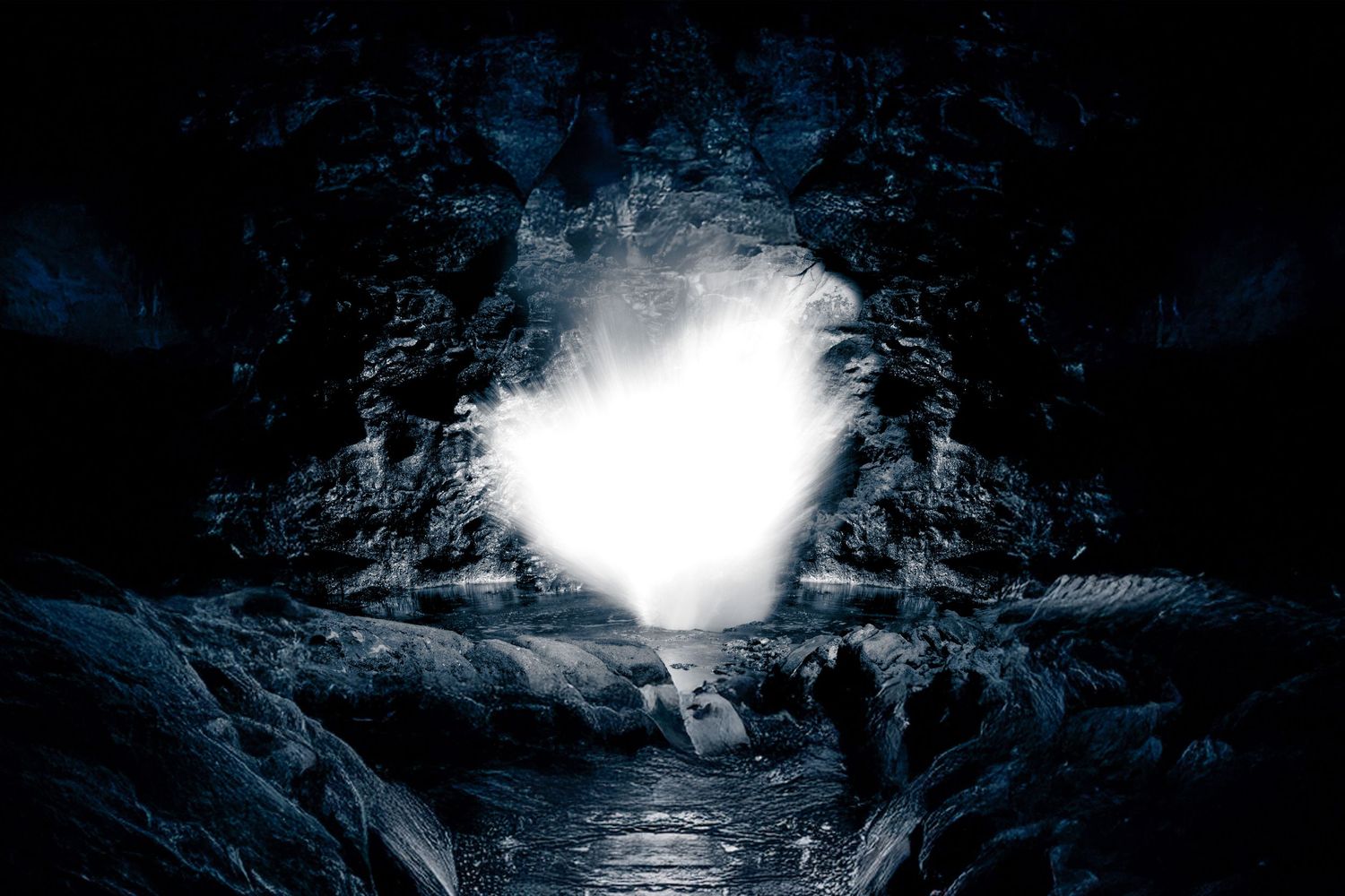 Dramatic low-light landscape of a bright light source reflecting at the end of a dark, narrow cavern or canyon.