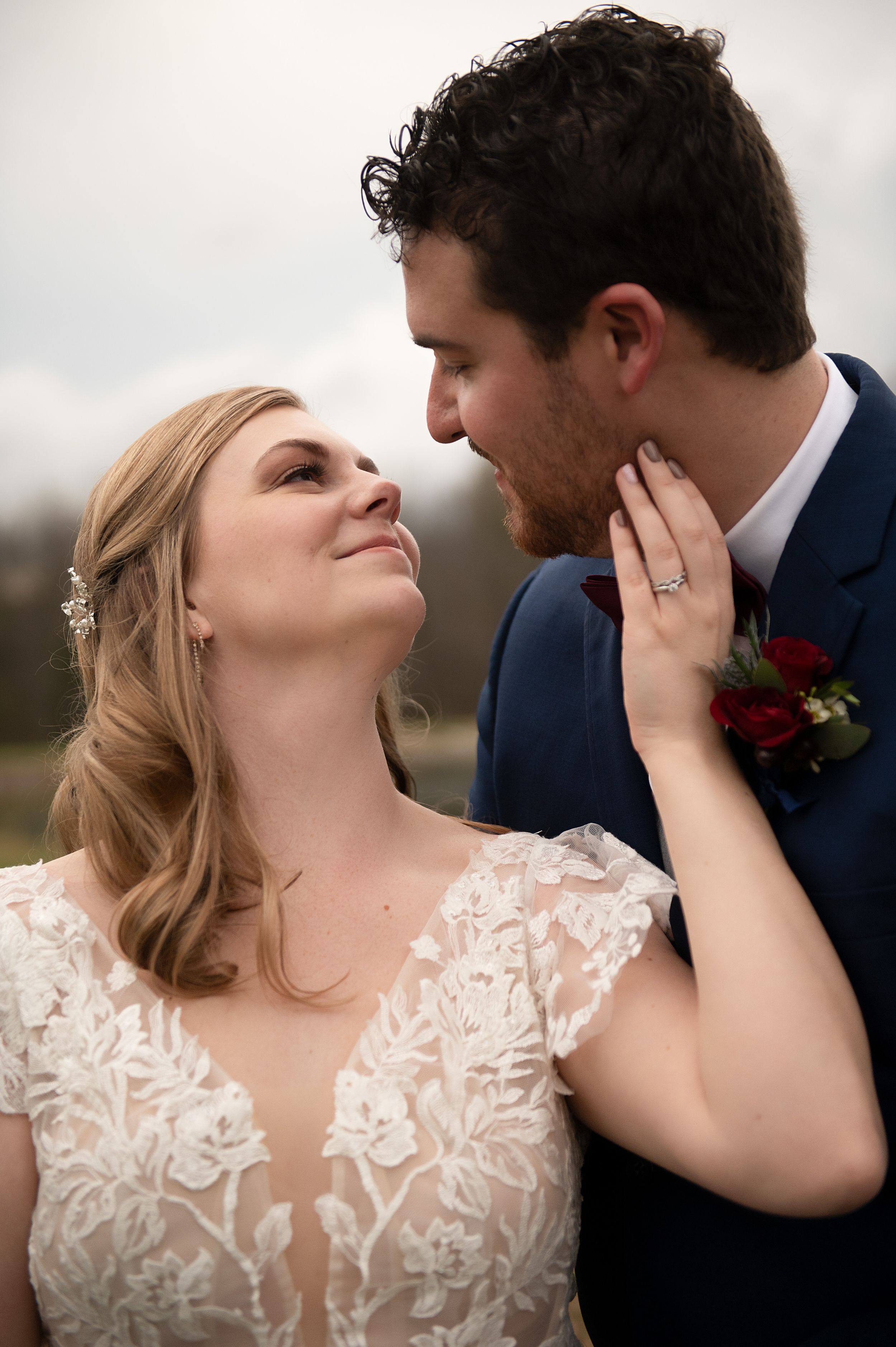 A romantic wedding moment showing tender affection between bride in lace and groom in navy.