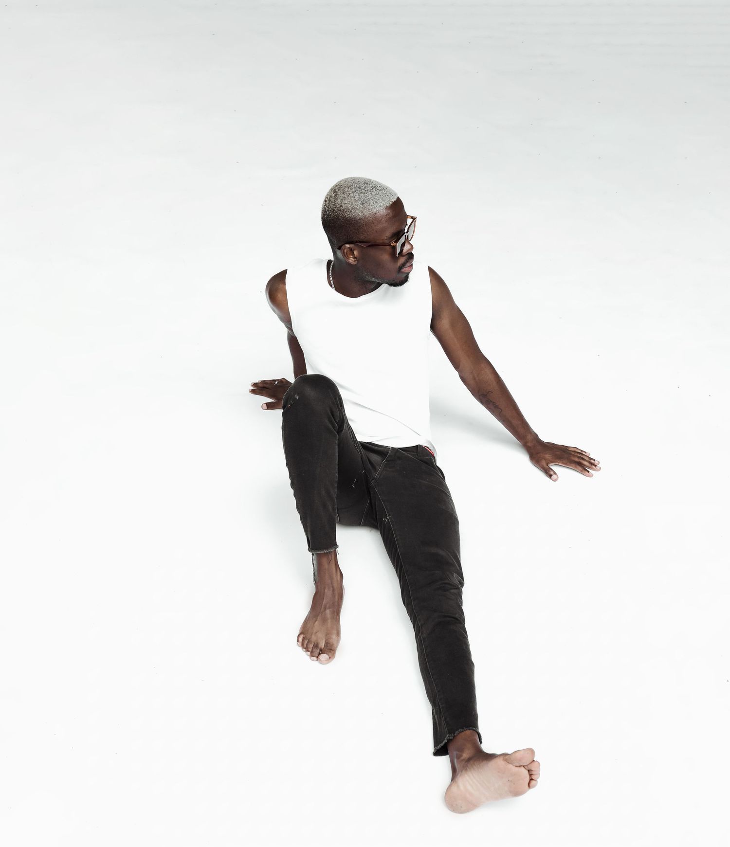 Contemporary dancer in casual attire performing dynamic movement against white background.