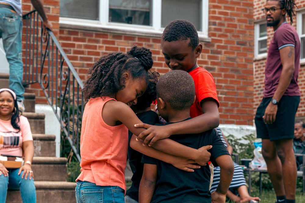 Community members socializing during an outdoor gathering near brick apartments.
