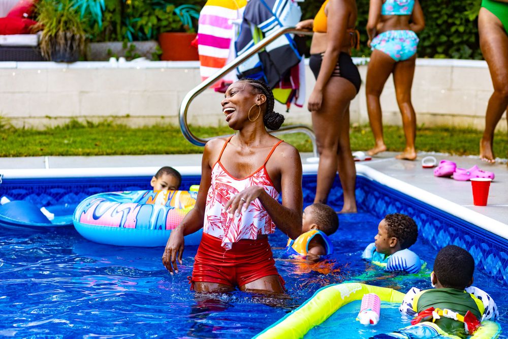 Group enjoying summer fun in a bright blue swimming pool.