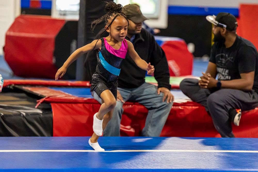 Children playing and exercising on blue gymnastics mats in a fitness facility.