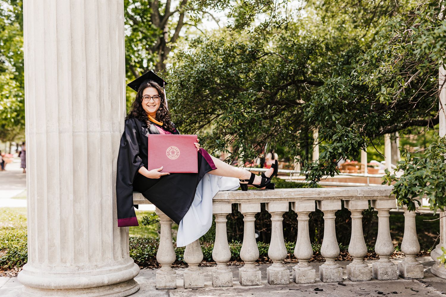 A graduation photo taken by a classic white stone column and decorative railing.