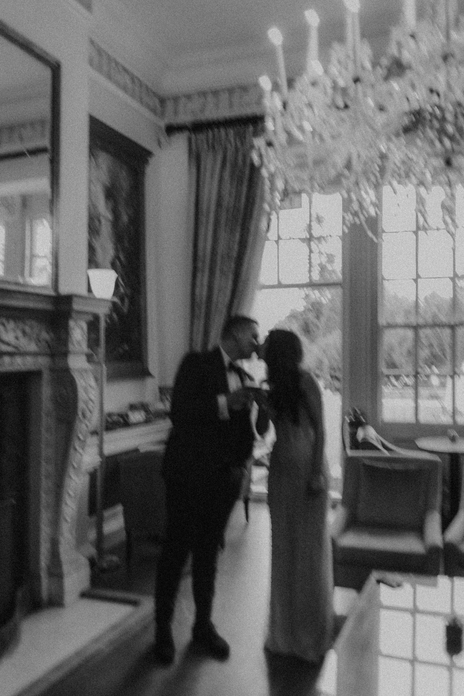 A vintage-style black and white photo of a couple in an elegant interior with chandelier.