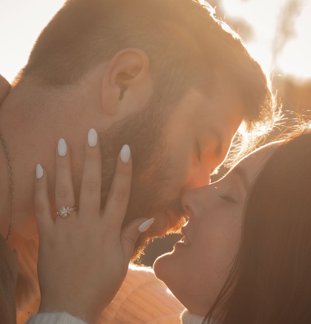 Backlit engagement photo showing ring and intimate moment at golden hour.