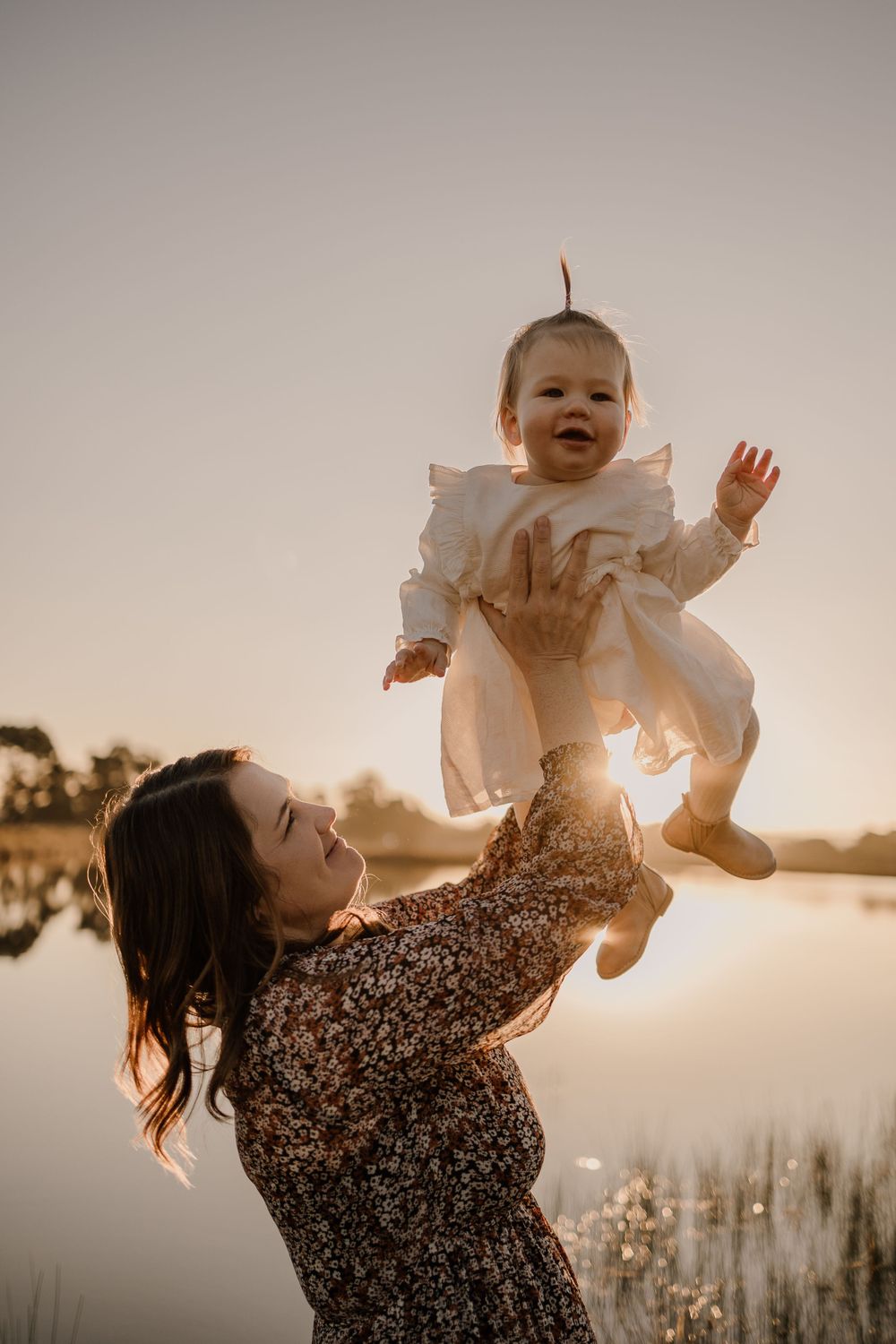 A joyful moment captured at golden hour by a peaceful lake with reflections in the water.