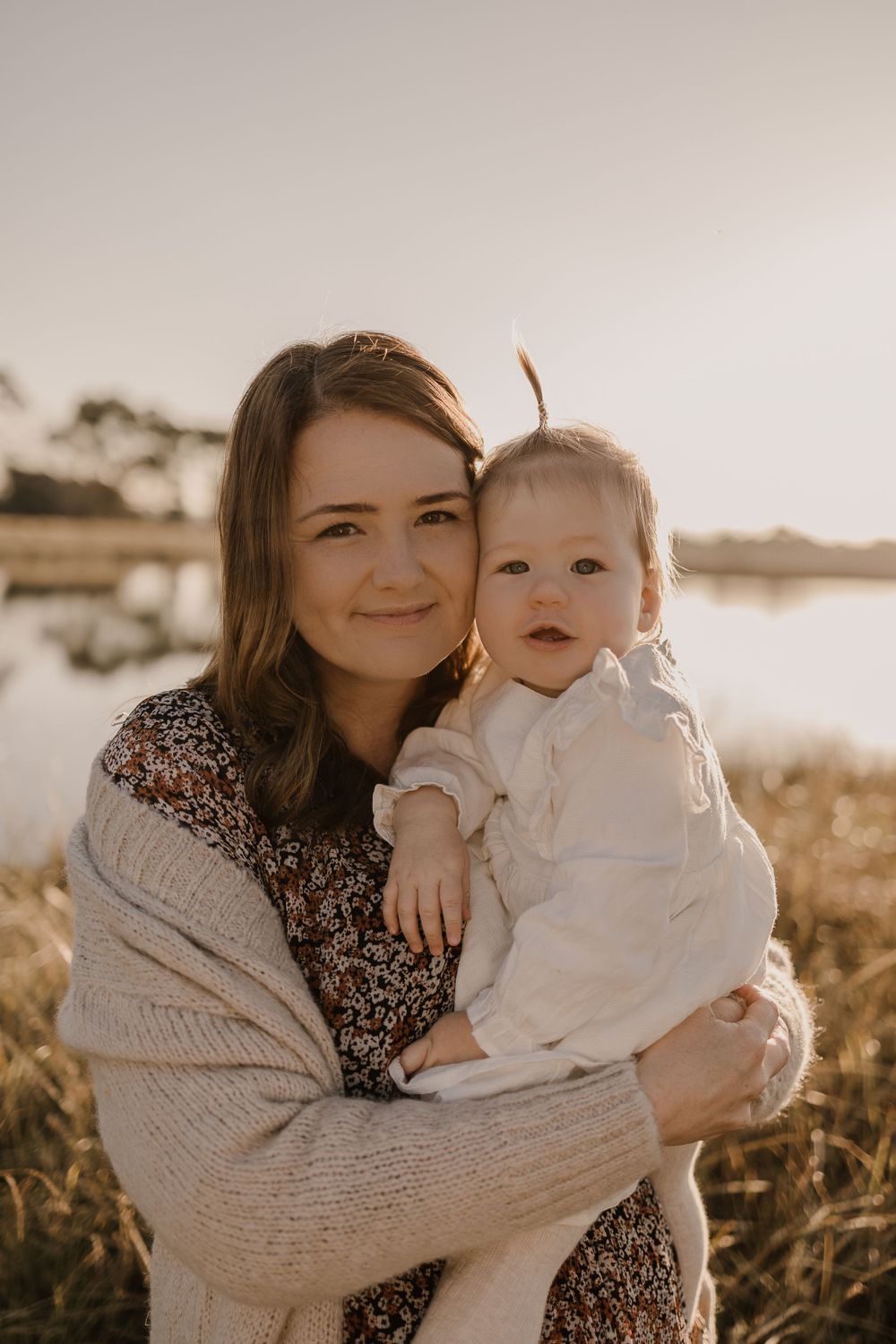 A warm sunset portrait of parent and child embracing by a lake.