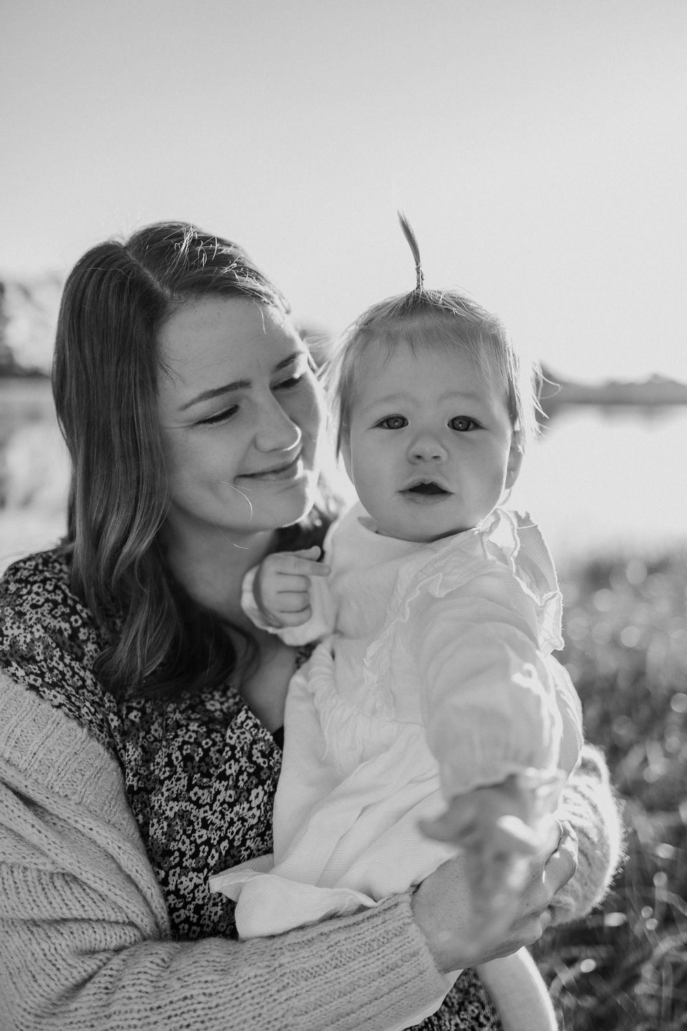 A tender moment captured between a parent and baby outdoors in black and white photography.