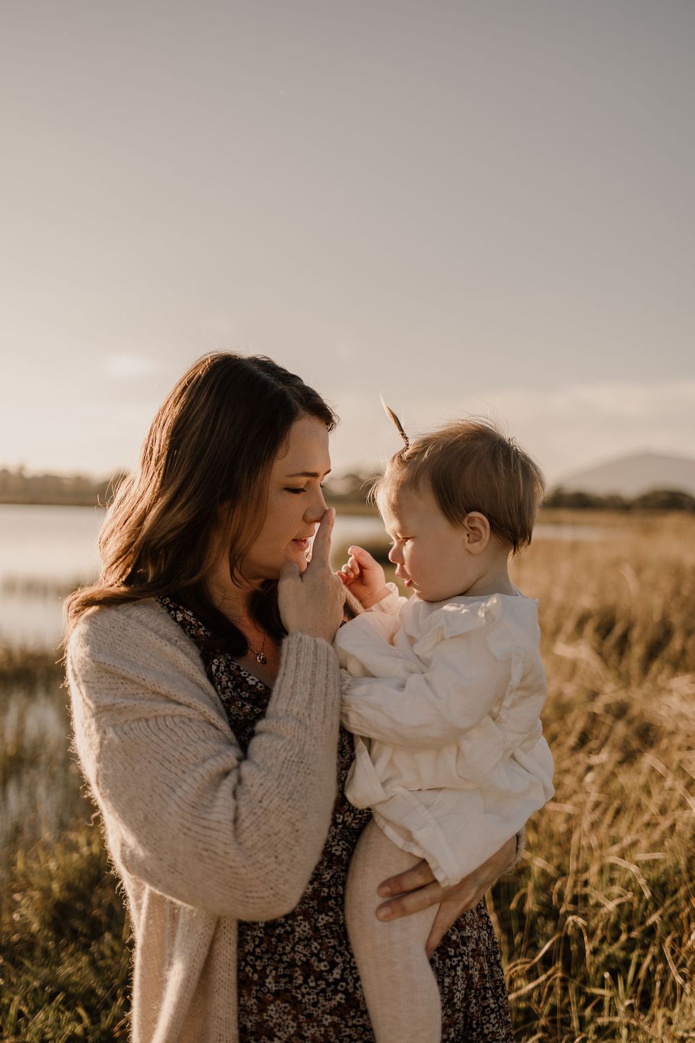 Candid outdoor portrait of parent and infant sharing an intimate moment in autumn sunlight.