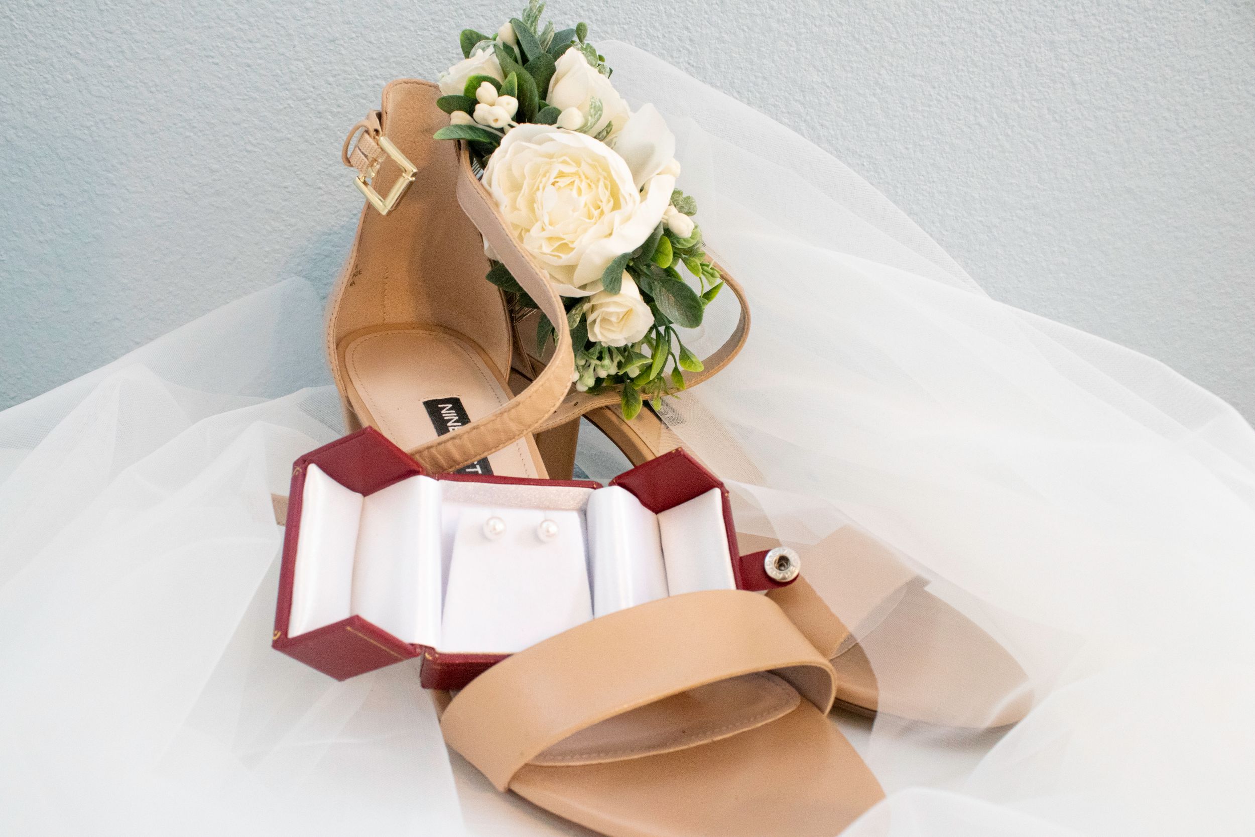 Elegant cream-colored ballet flats with floral accents and ribbons arranged in a minimalist style against a white background.