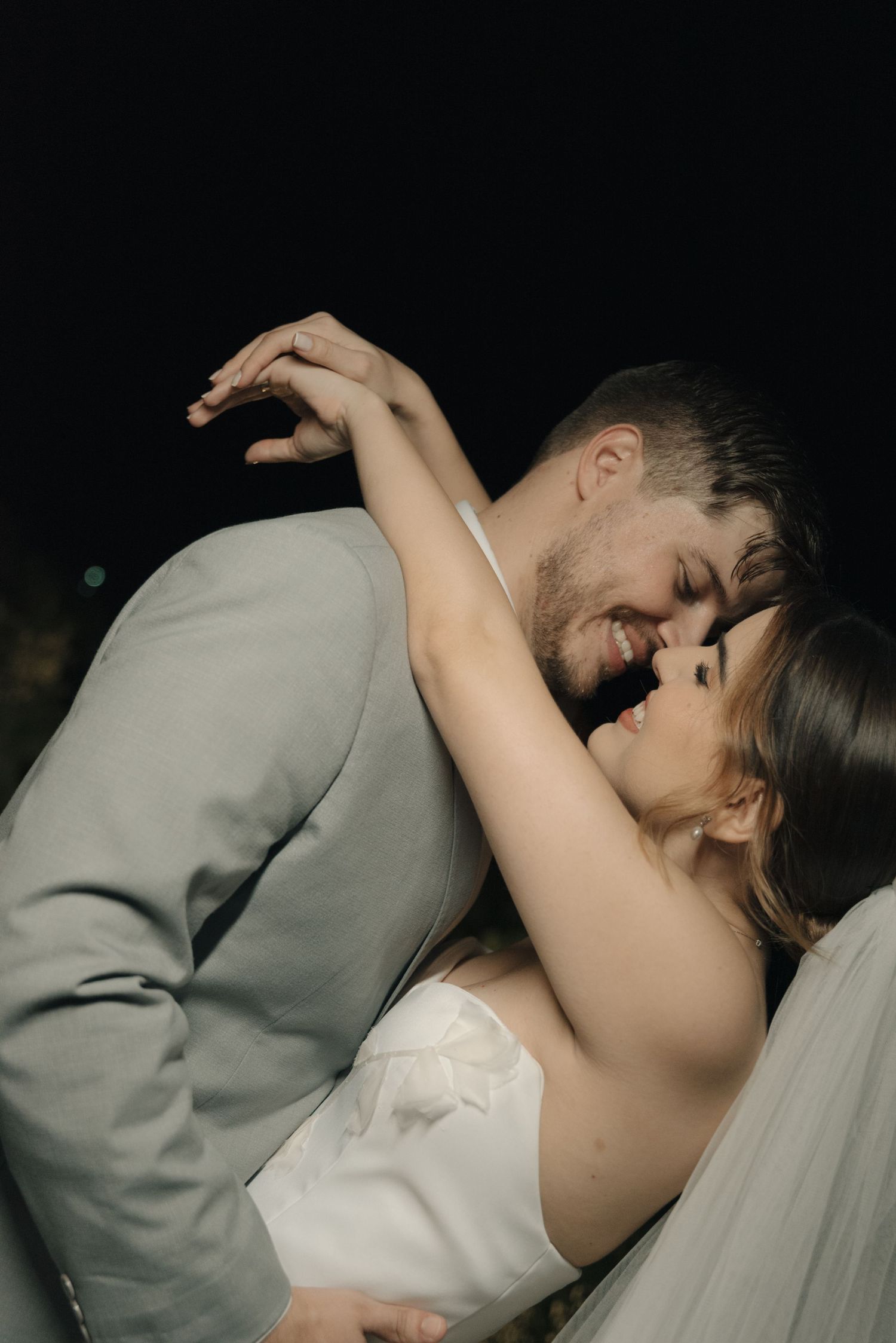 Dramatic wedding photo with couple in intimate embrace under evening sky.