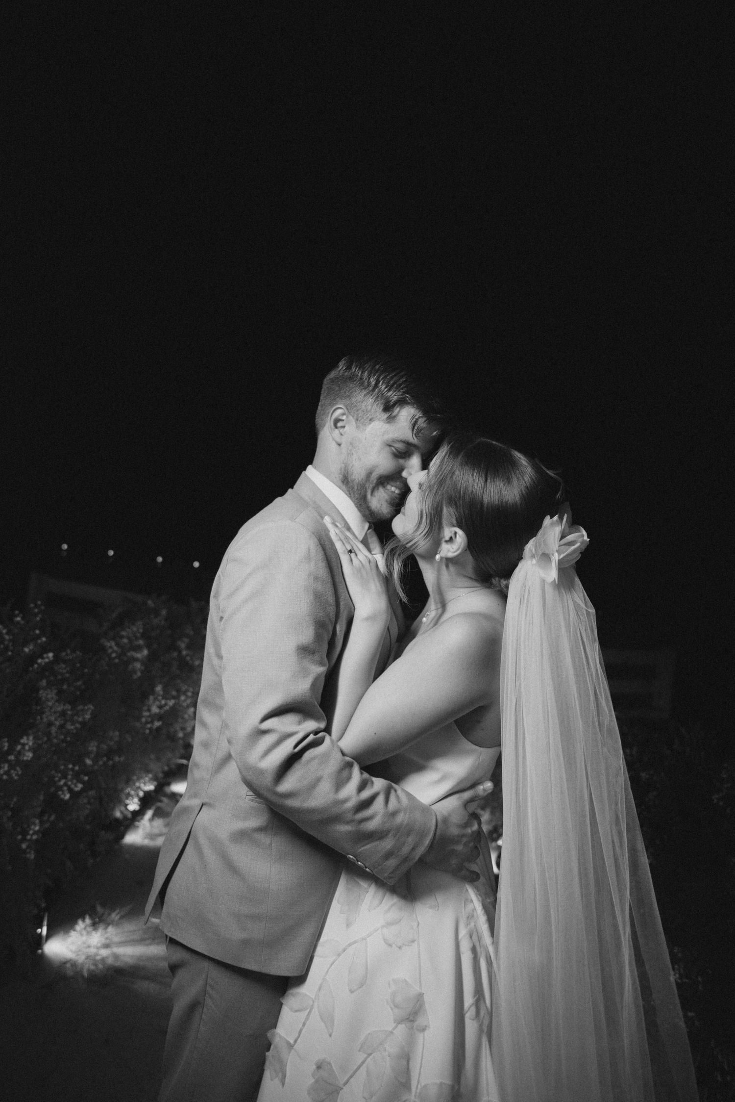 Black and white wedding portrait capturing romantic moment between newlyweds.