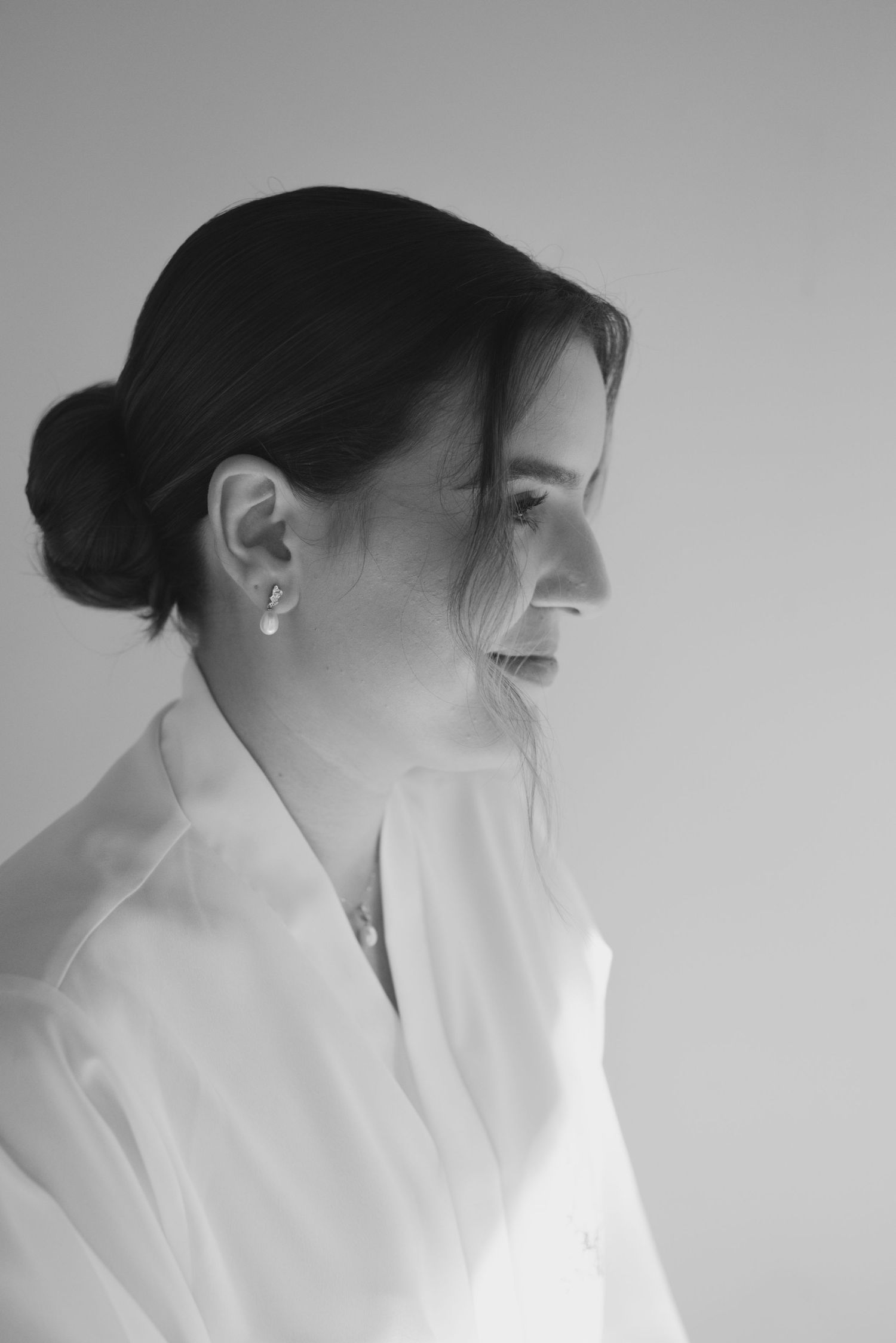 Side profile portrait of person in white robe with elegant hair bun.