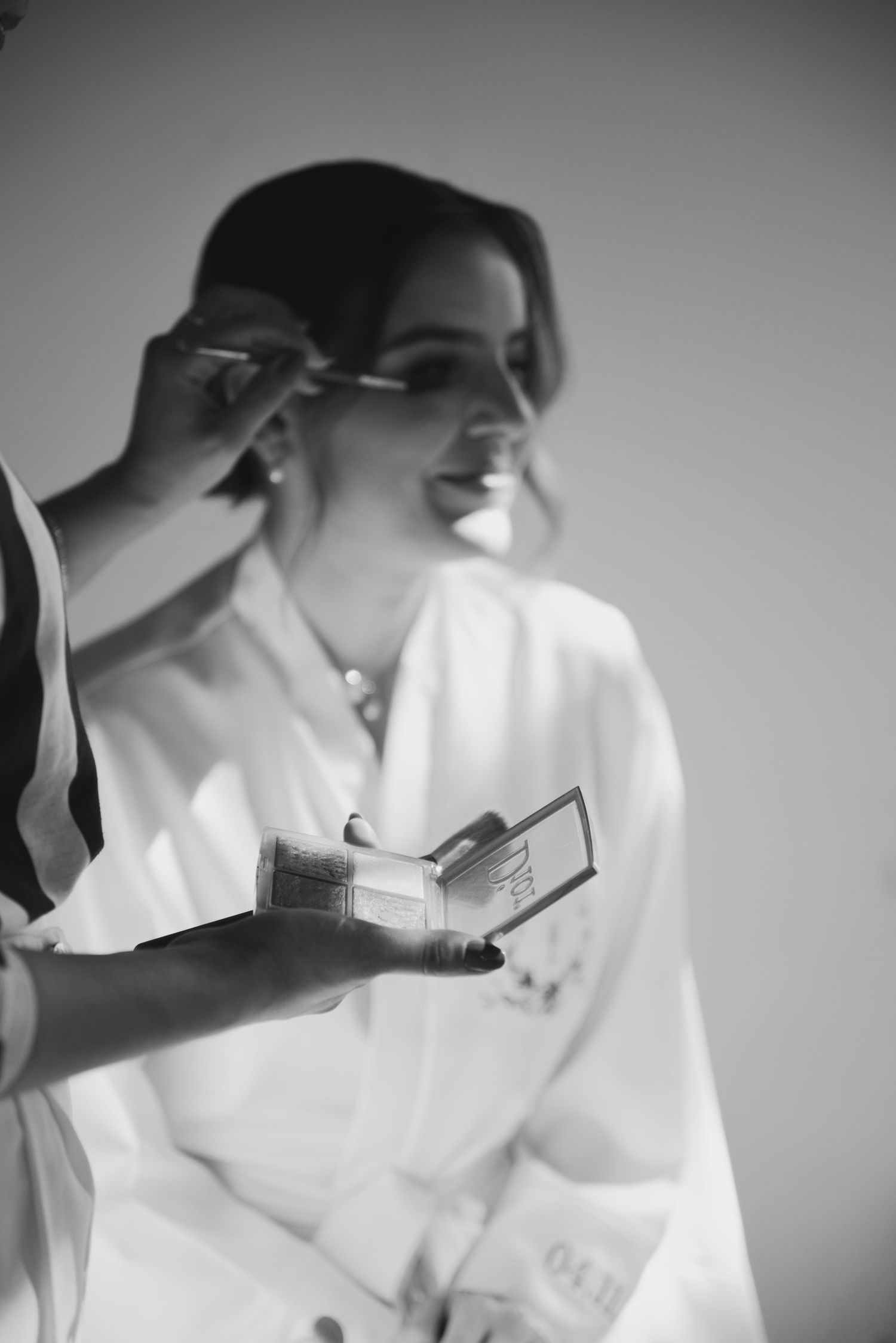 Getting ready scene with makeup application in black and white photography.