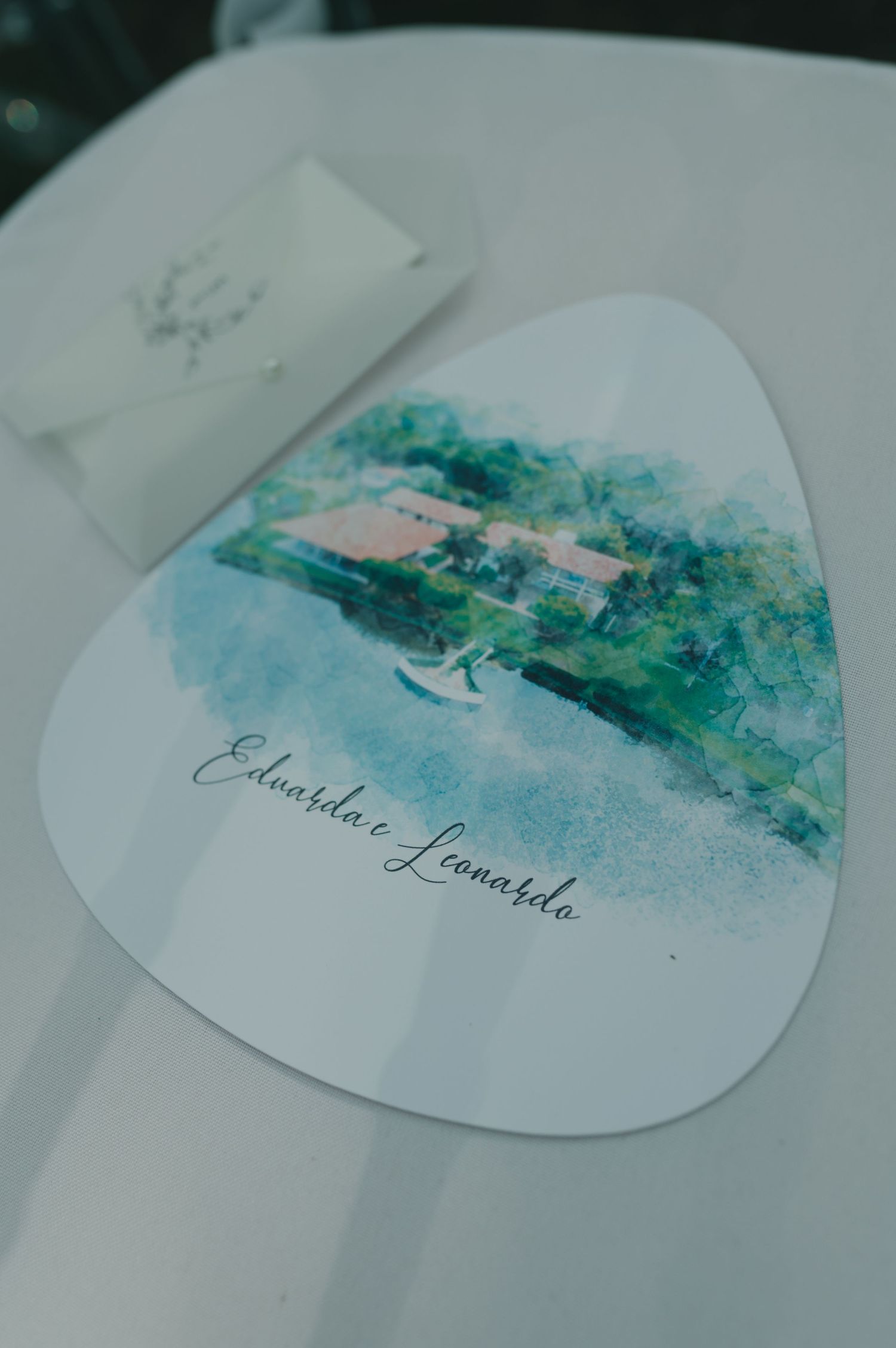 Watercolor wedding invitation featuring a blue and green landscape scene with decorative text.