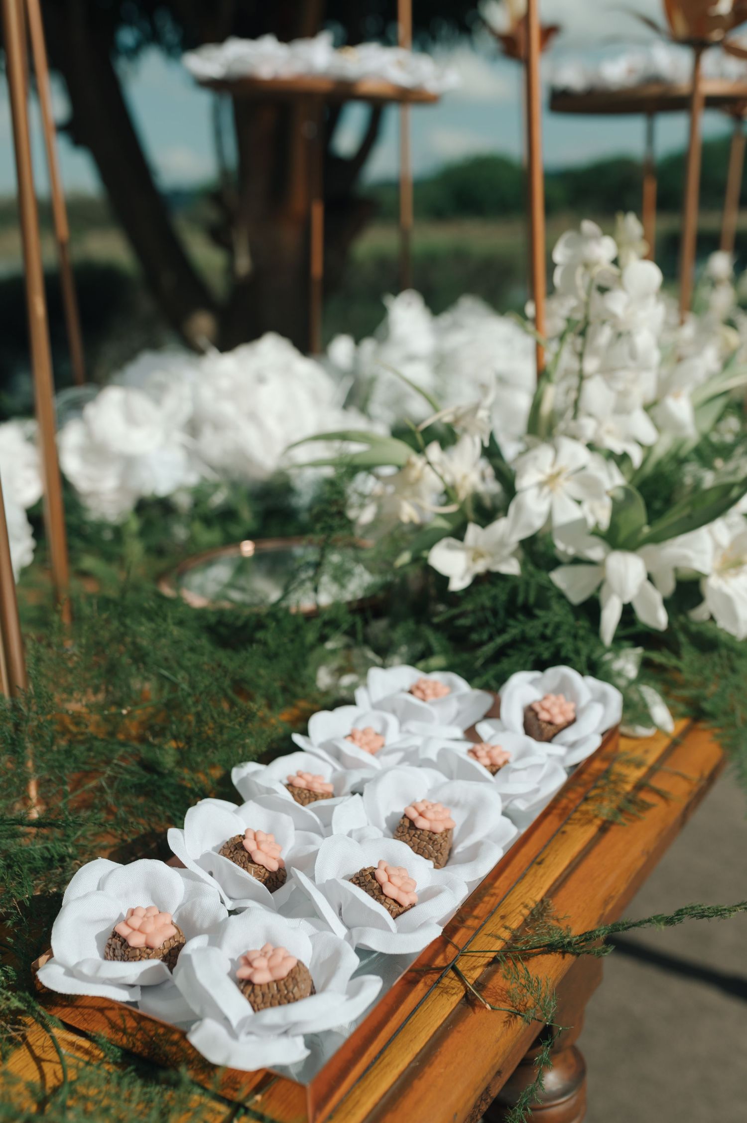 Wedding appetizers elegantly displayed on white paper with floral decorations.