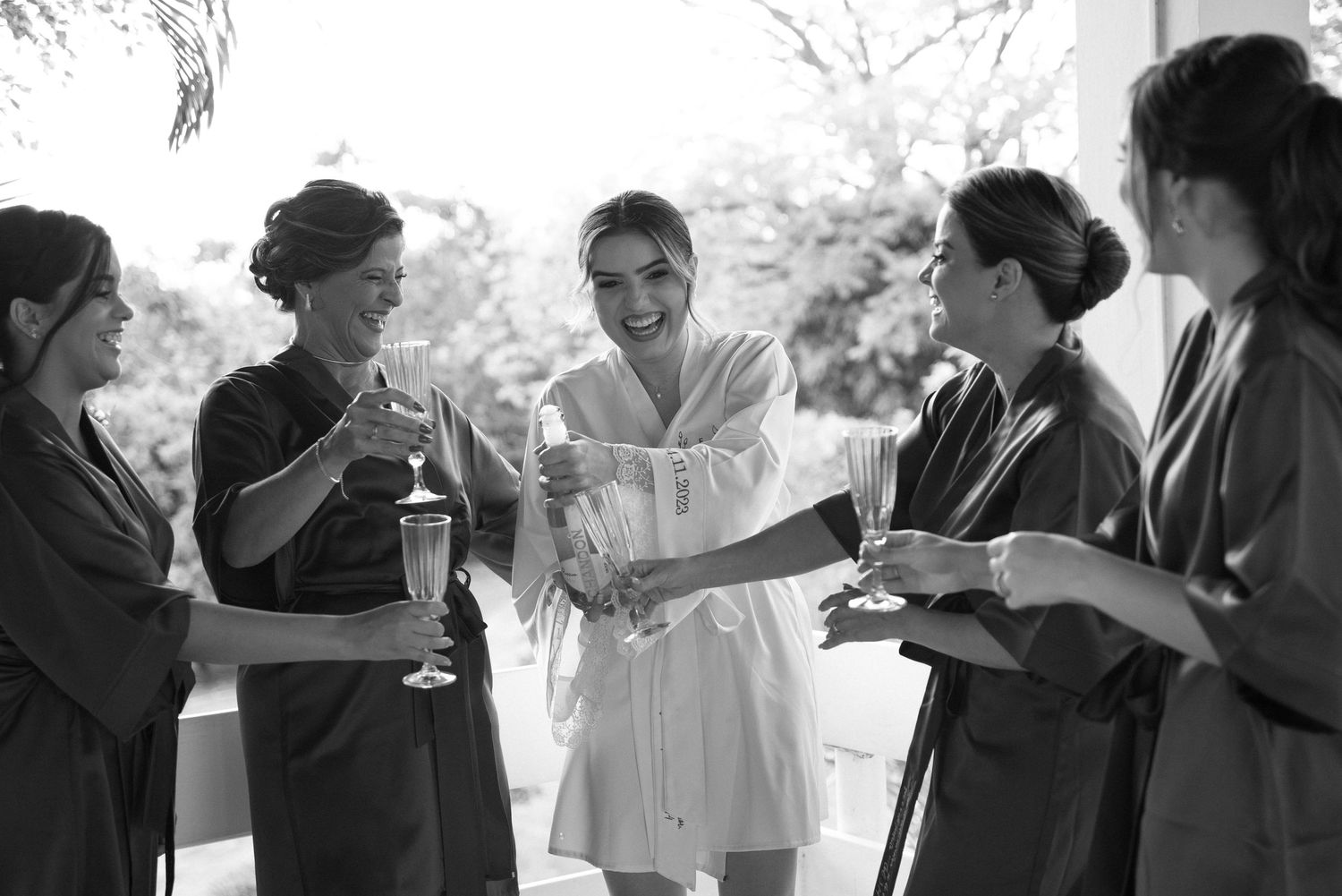 Black and white photo of wedding preparation with attendants enjoying refreshments.