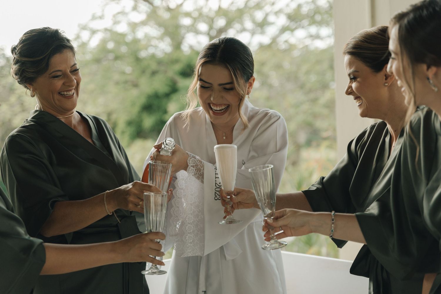 Candid moment of wedding party members toasting and laughing together.