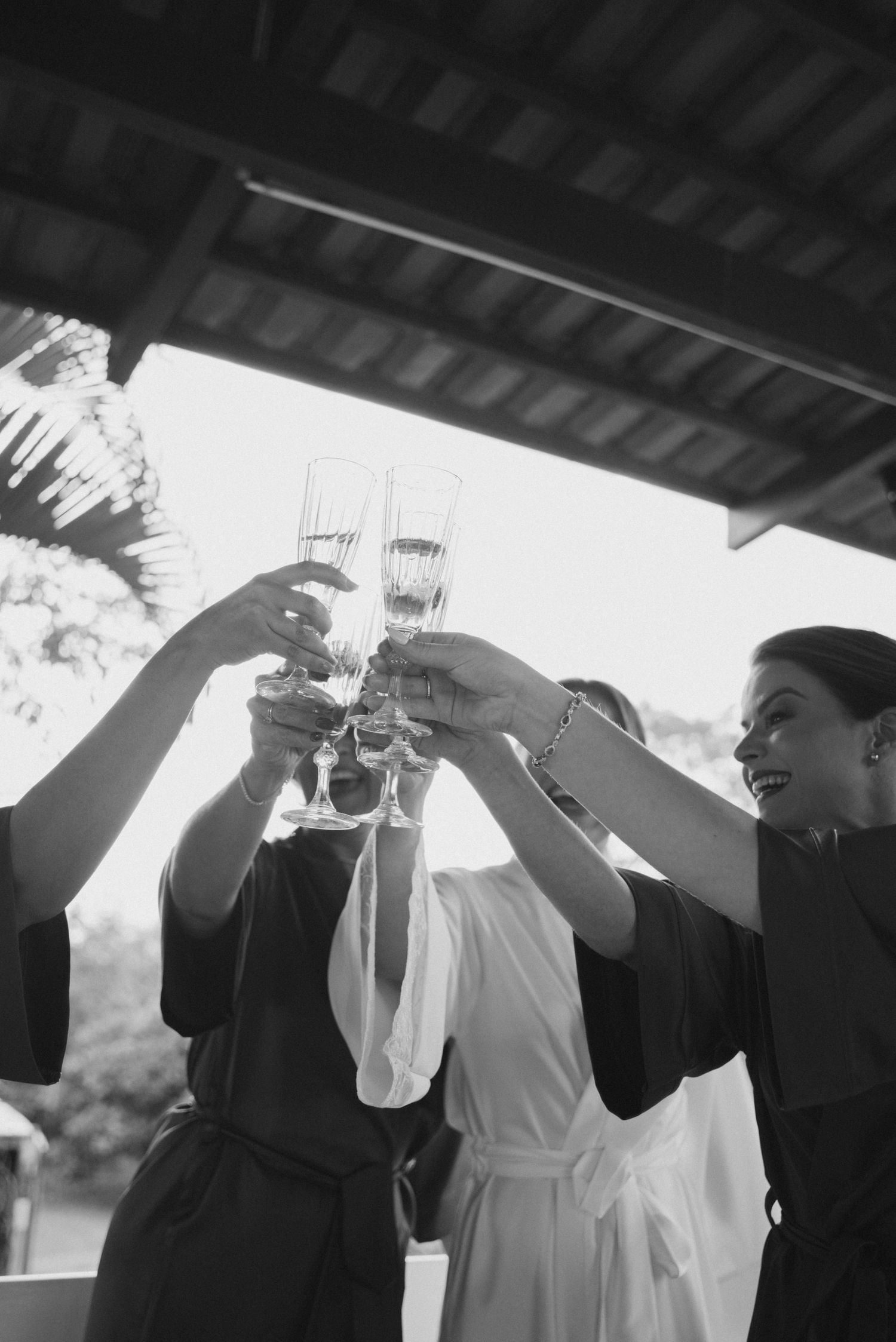 Black and white photo of a celebratory champagne toast under covered patio.