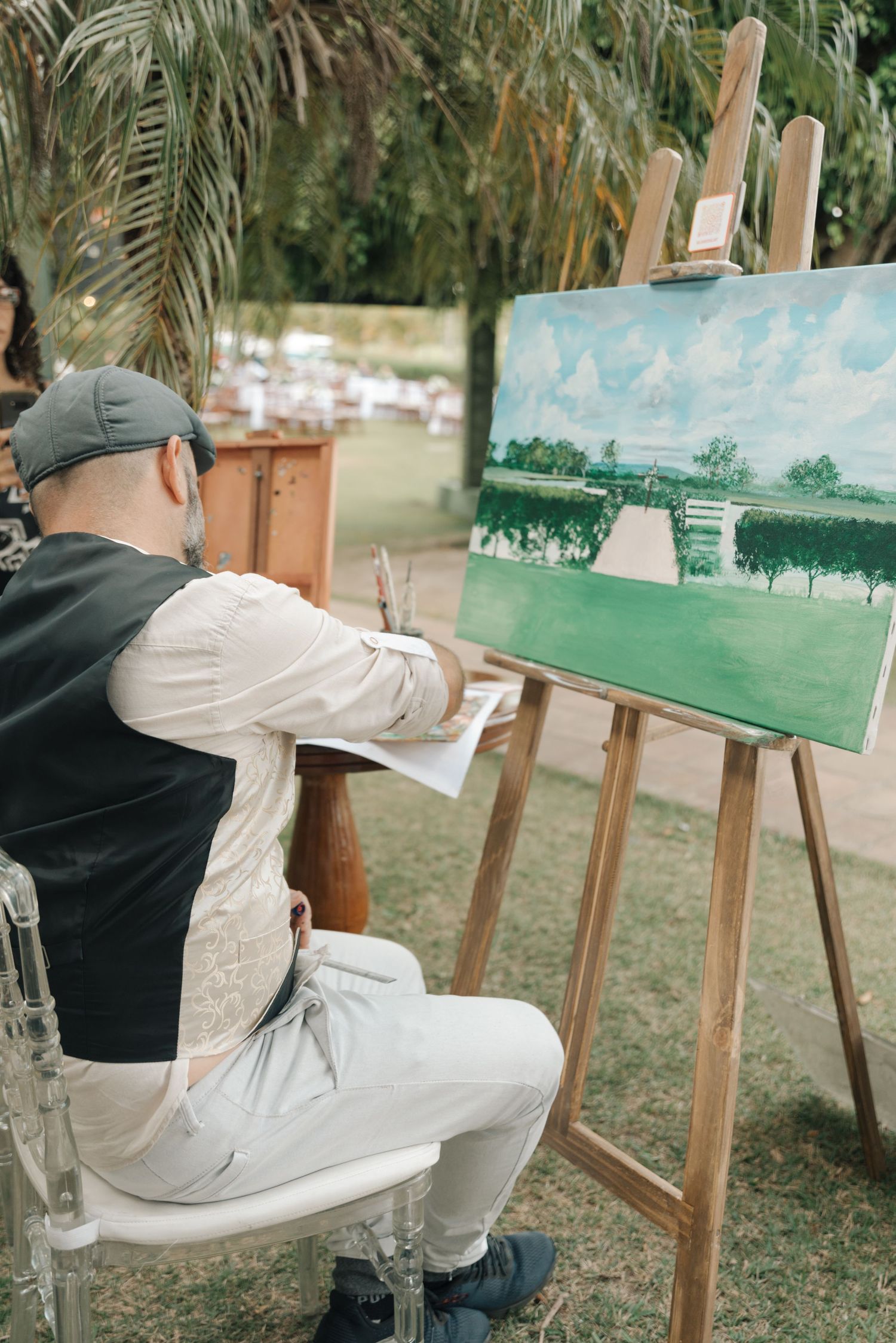 Artist painting a watercolor landscape scene at an outdoor wedding venue.