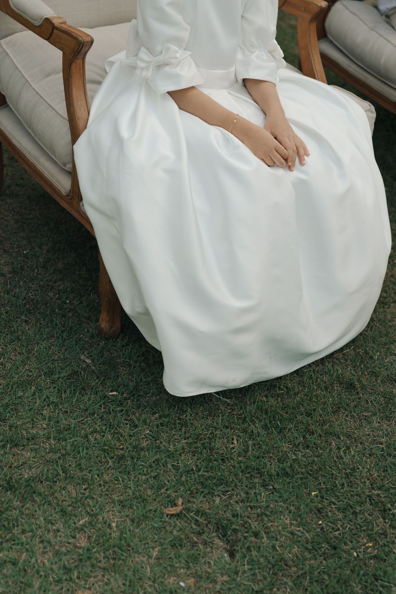 Close-up of flowing white wedding dress fabric draped over vintage chair.