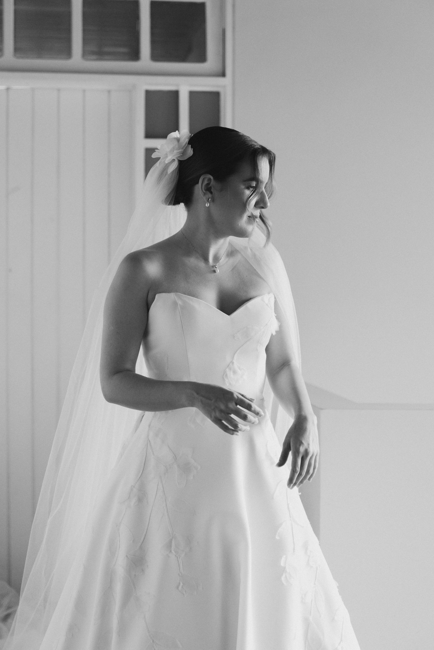A stunning black and white portrait of a bride in a strapless wedding gown and veil looking to the side.