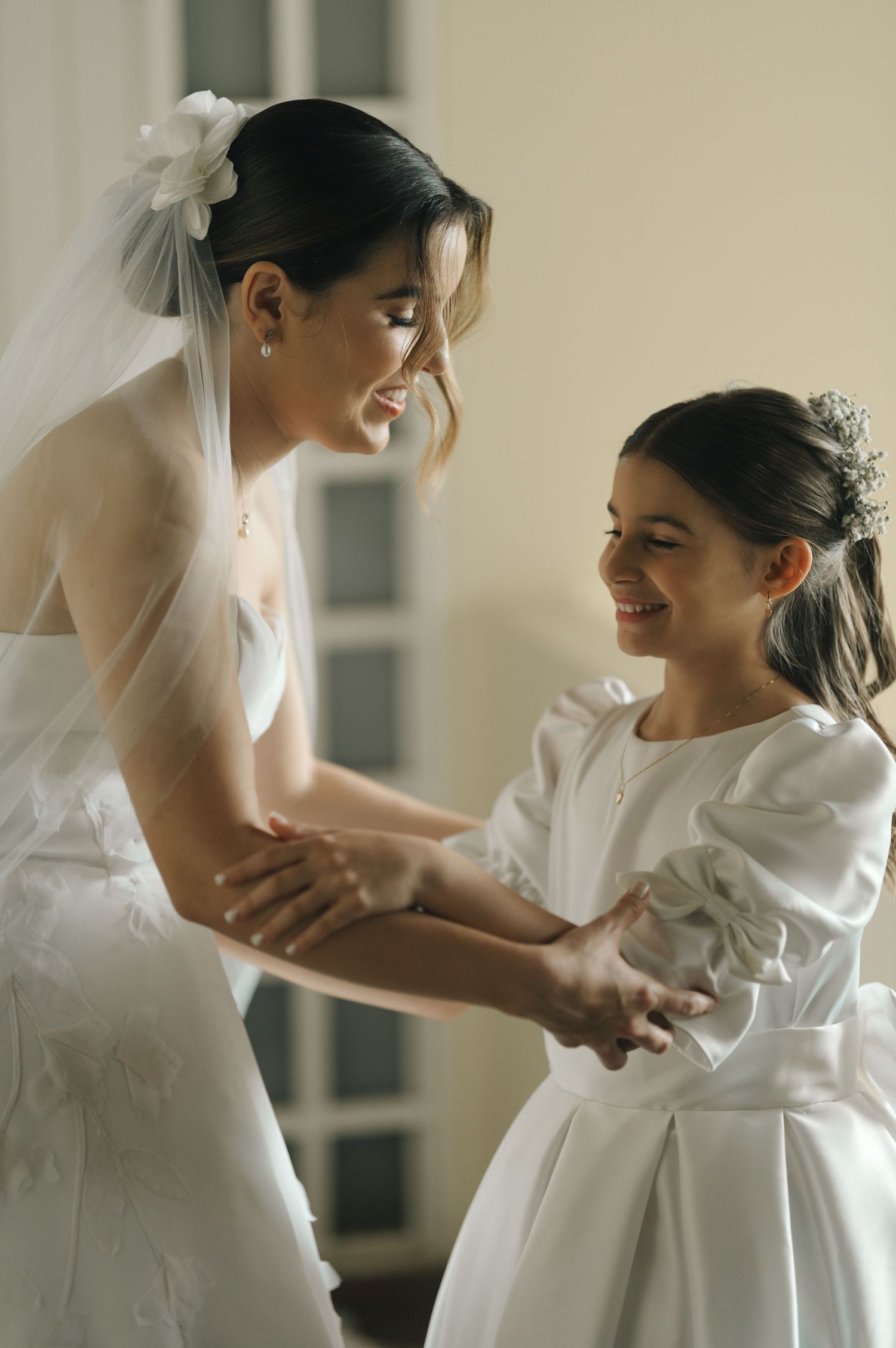 Sweet moment between a bride in white and a young girl in a flowing white dress sharing a special moment.