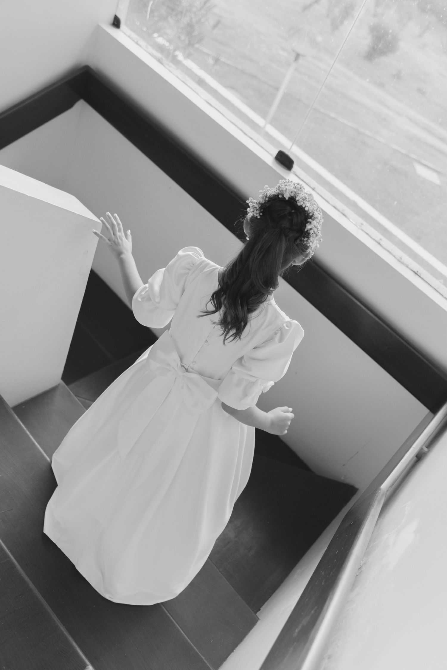 A figure in a white flowing dress spins joyfully in a stairwell, captured in black and white.