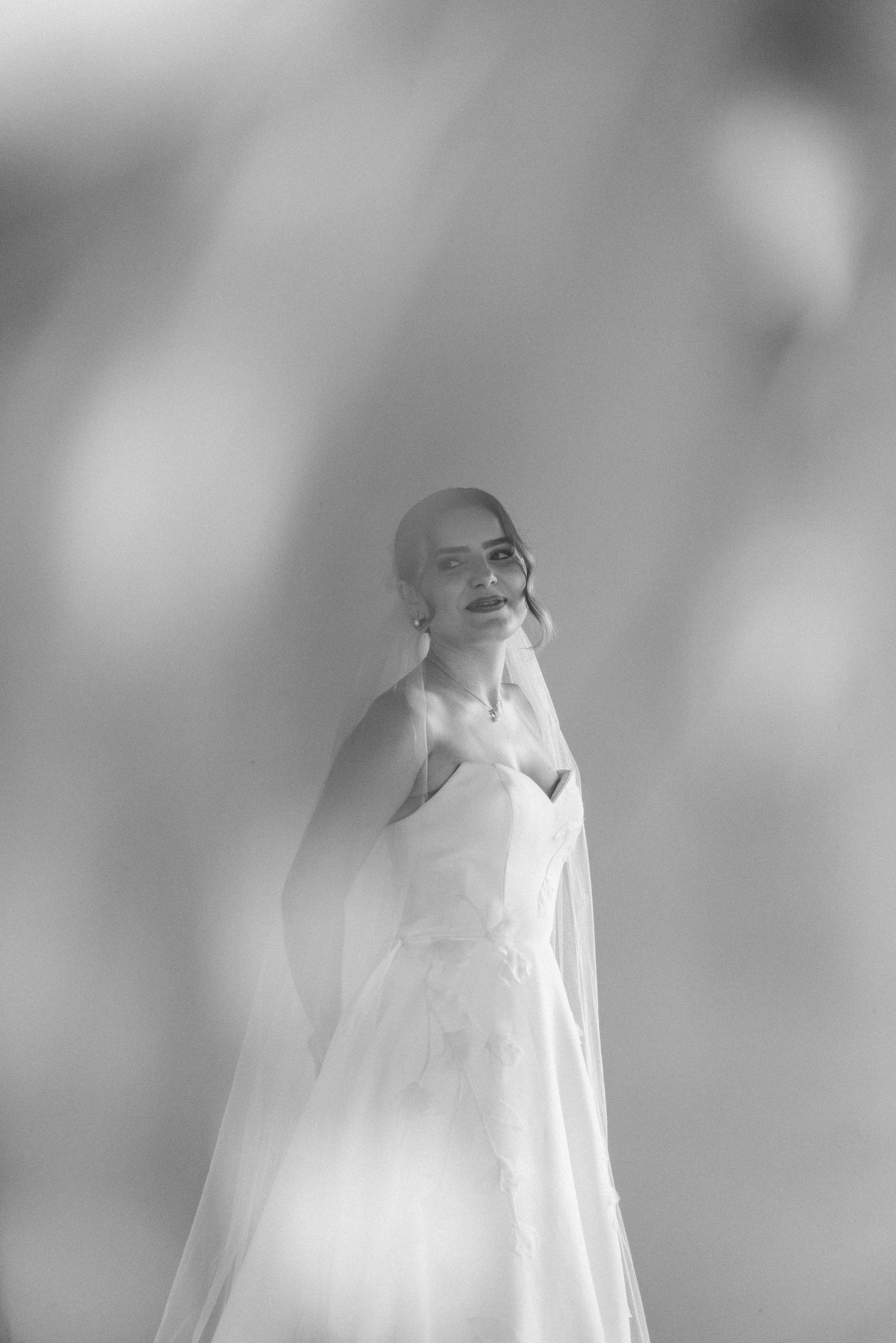 A dreamy black and white portrait of a bride in a traditional wedding gown with veil.