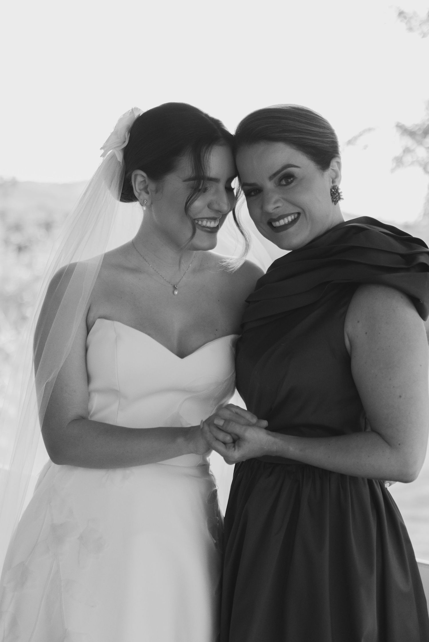 Two wedding attendees share a joyful moment in black and white photography.
