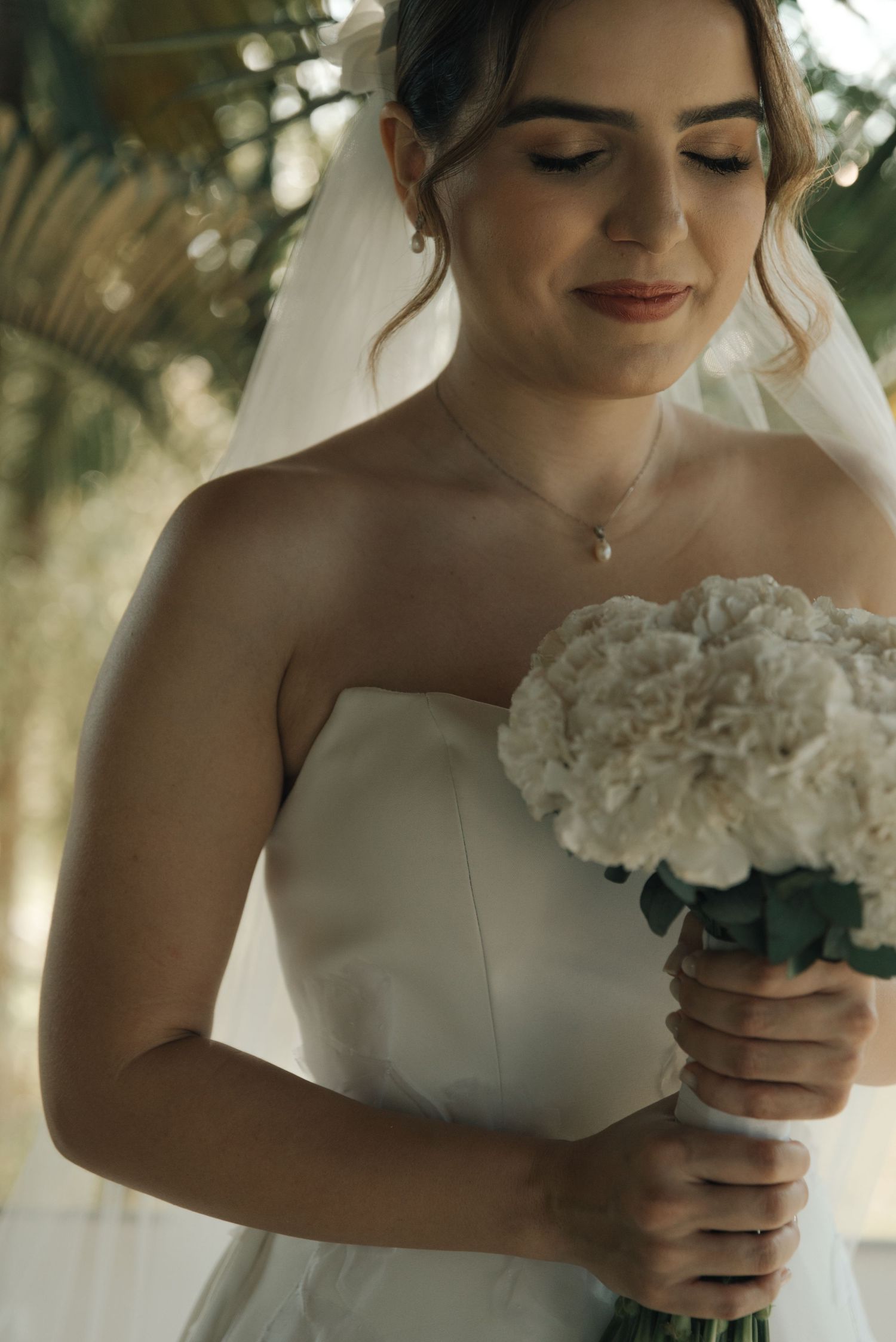 Close-up of a bride holding white bouquet with soft natural lighting.