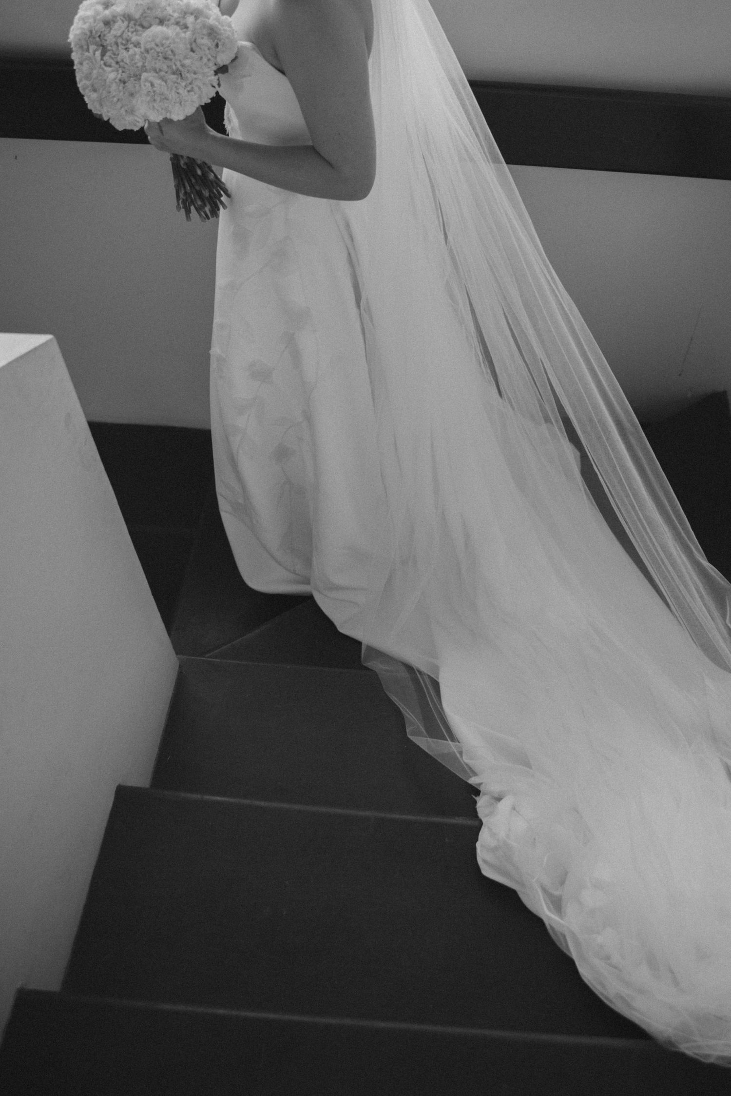 Black and white photo of bride's dress train flowing down stairs.