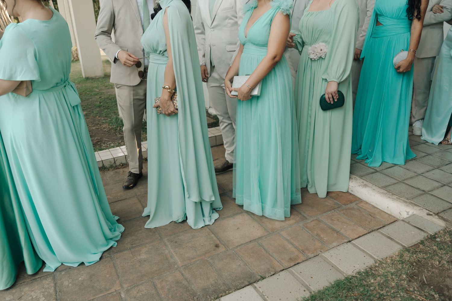 Row of bridesmaids in mint green dresses standing together at outdoor wedding.